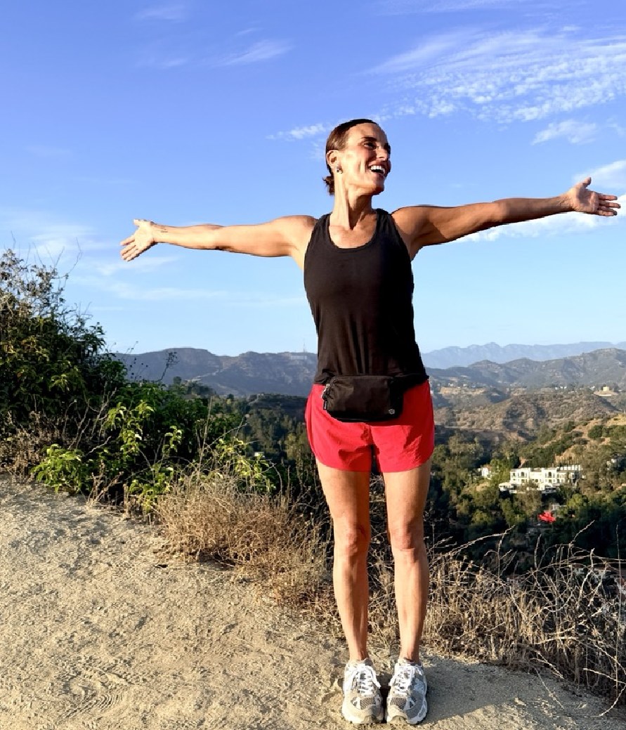 Heidi D'Amelio with open arms on a hilltop trail